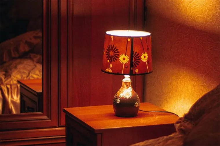Warm bedside lamp on a wooden nightstand in a dark bedroom
