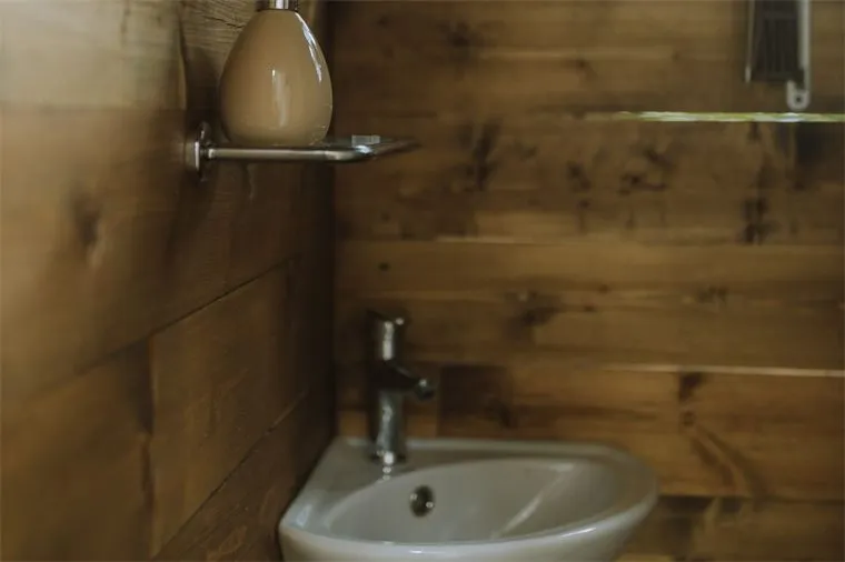 Small wooden bathroom with a compact white sink