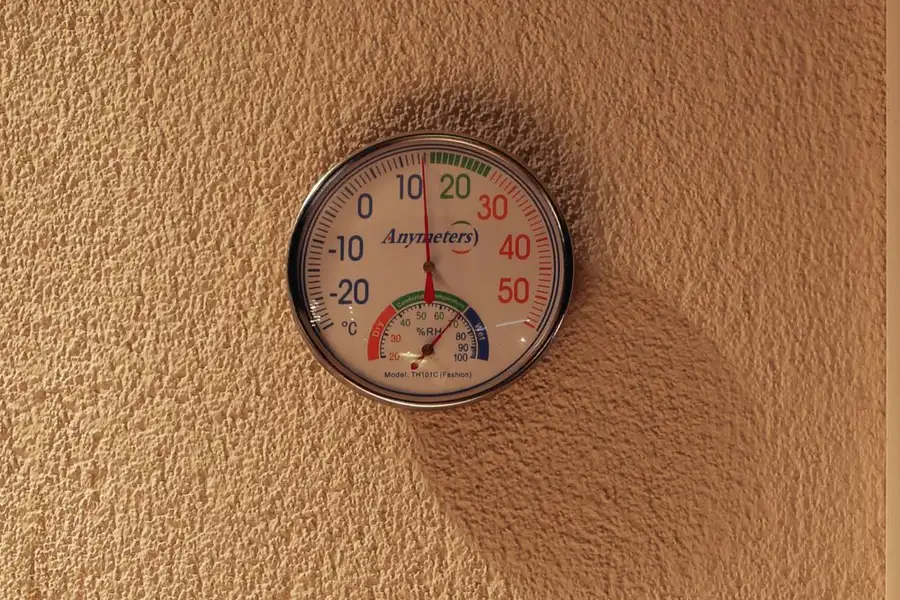 A round wall thermometer and hygrometer with a percent relative humidity dial, the kind of gauge that shows whether room air is dry enough for an evaporative cooler