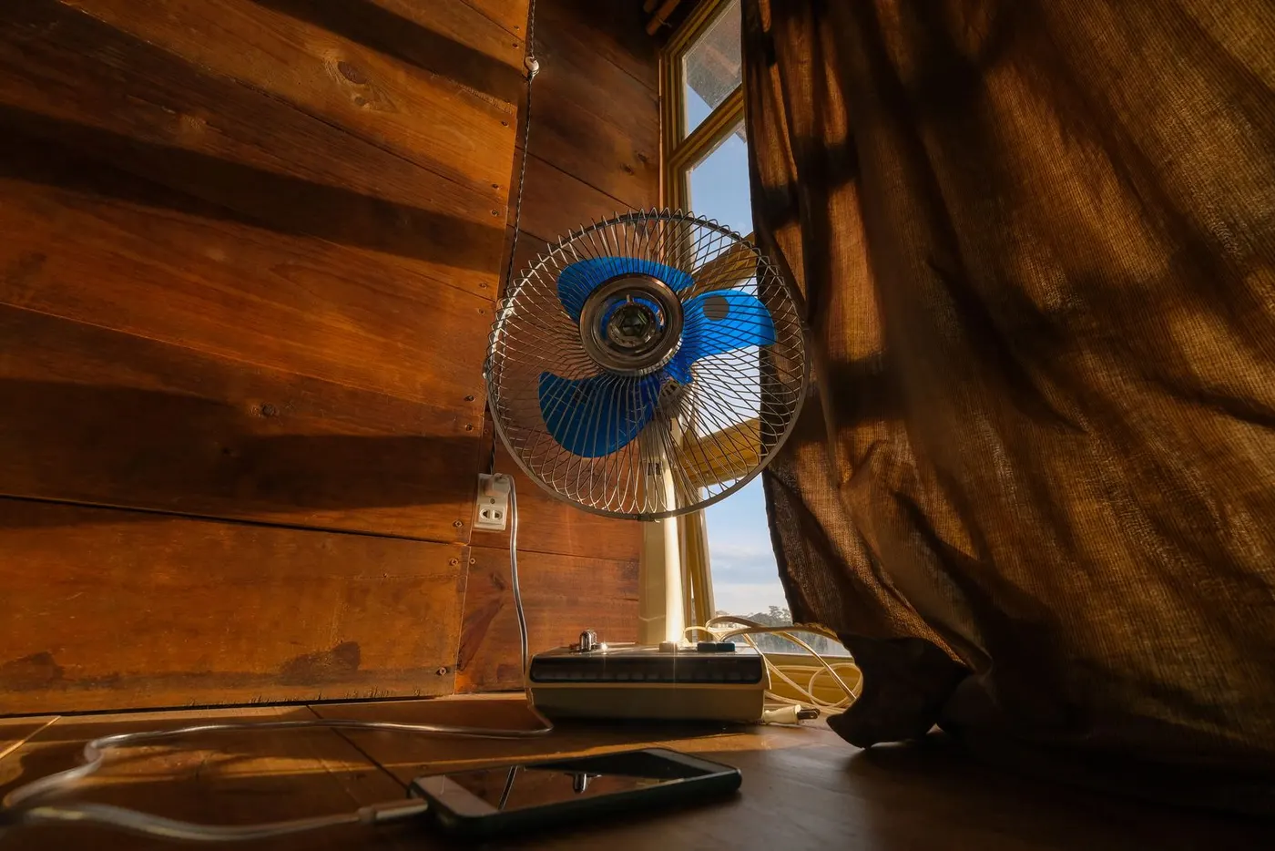 Portable fan running in a bright summer room to circulate air on a warm afternoon