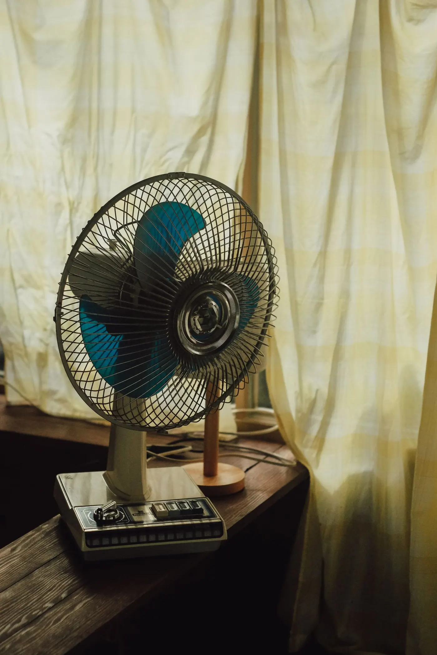 Portable fan by a sunlit window in a summer room — the closest visual cousin to an evaporative cooler