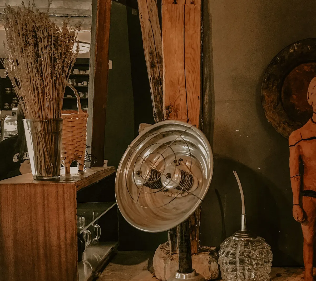 A vintage reflector-style electric heater on a shelf with dried lavender, a wicker basket and a wooden beam right beside it